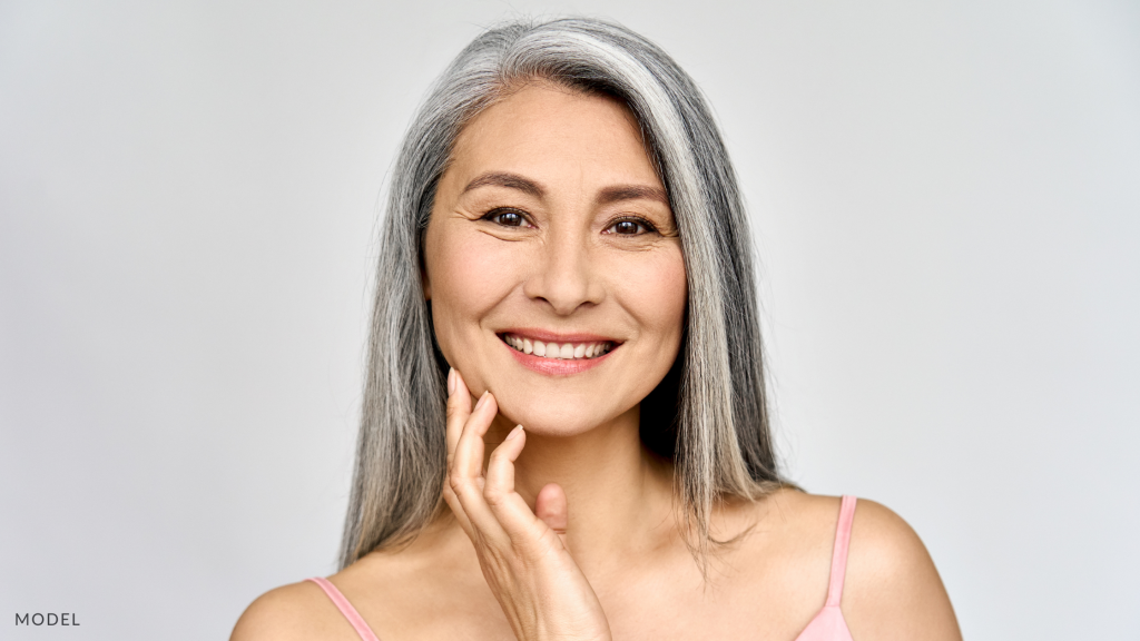 An older woman with long hair, touching her face (model)