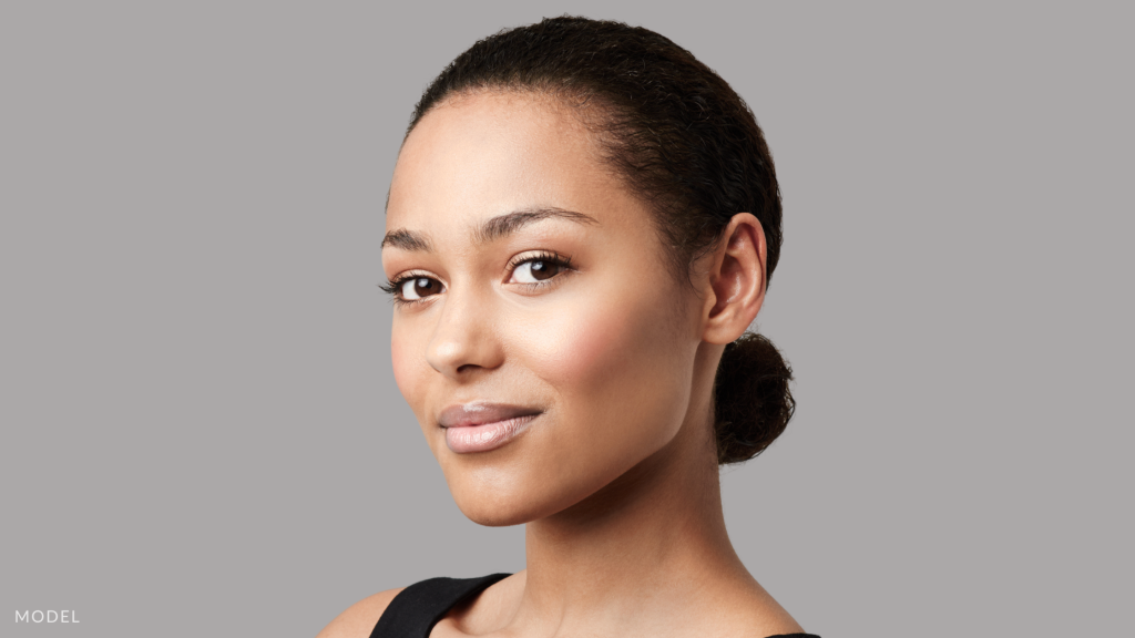 A woman with hair in a bun and clear skin (model)