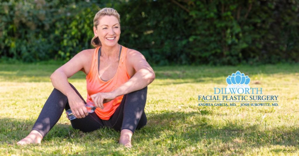 Woman wearing sportswear sitting in a park. (Model)